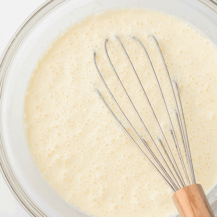 Whisking heavy cream, milk, sugar, and vanilla in a bowl to make the creamy ice cream base.