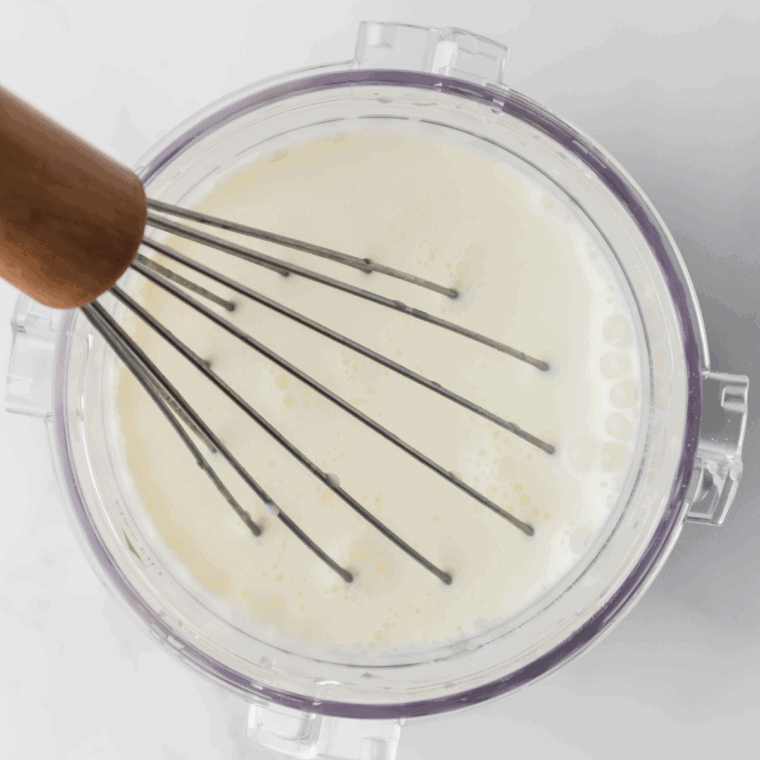 Whisking cream, milk, sugar, and extracts together in a mixing bowl.