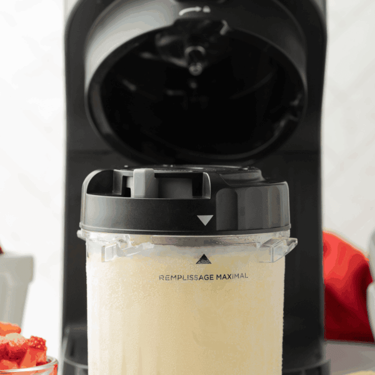Strawberry ice cream mixture poured into a Ninja Creami pint container, covered with lid, ready to freeze.