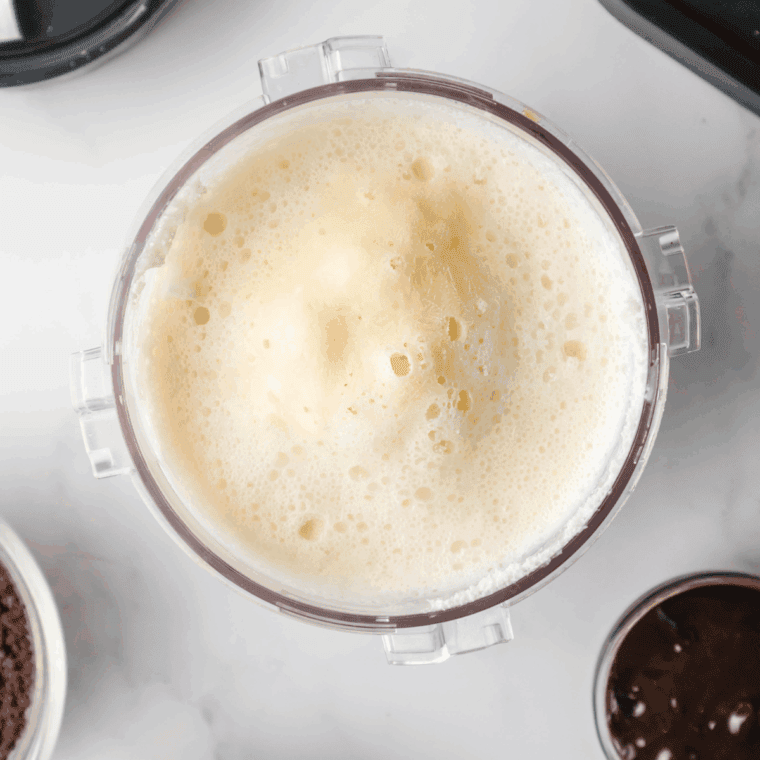 Pouring milk and heavy cream into a bowl to combine with the cream cheese mixture for the ice cream base.
