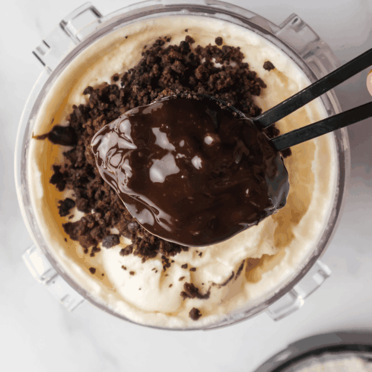 Adding chopped brownies, crushed Oreos, and fudge sauce into the center of the processed ice cream.