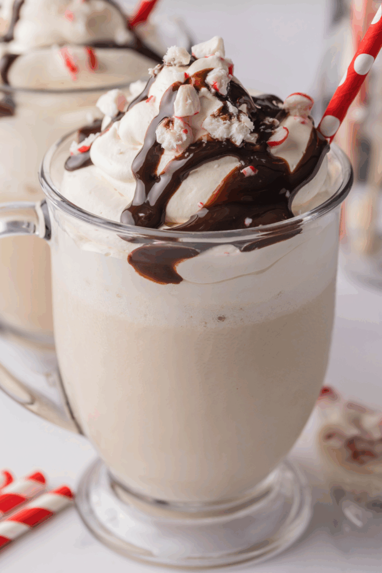 A glass of homemade Ninja Creami Starbucks Peppermint Mocha Creamiccino topped with whipped cream, chocolate drizzle, and crushed candy canes.