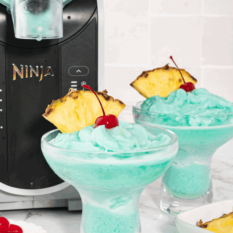 Ninja Slushi Blue Hawaiian Cocktail in a frosty glass with a straw and tropical garnish.