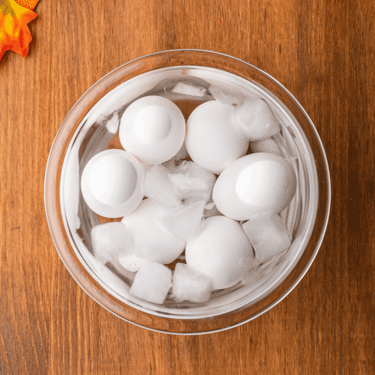 Hard-boiled eggs cooling in an ice bath to stop cooking and loosen shells.