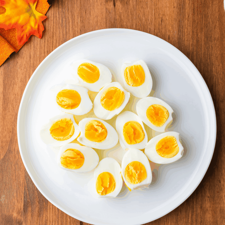 Peeled hard-boiled eggs sliced in half with yolks removed and placed in a bowl.