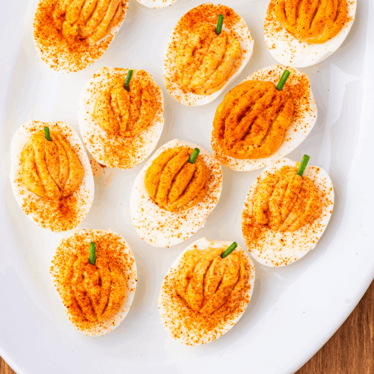 Pumpkin-shaped deviled eggs with creamy yolk filling, paprika, and chive stems, perfect for Halloween or Thanksgiving.