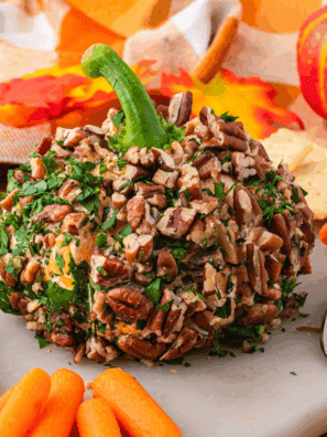Pumpkin-shaped cheese ball served on a platter with crackers and herbs for a festive Halloween or Thanksgiving appetizer.
