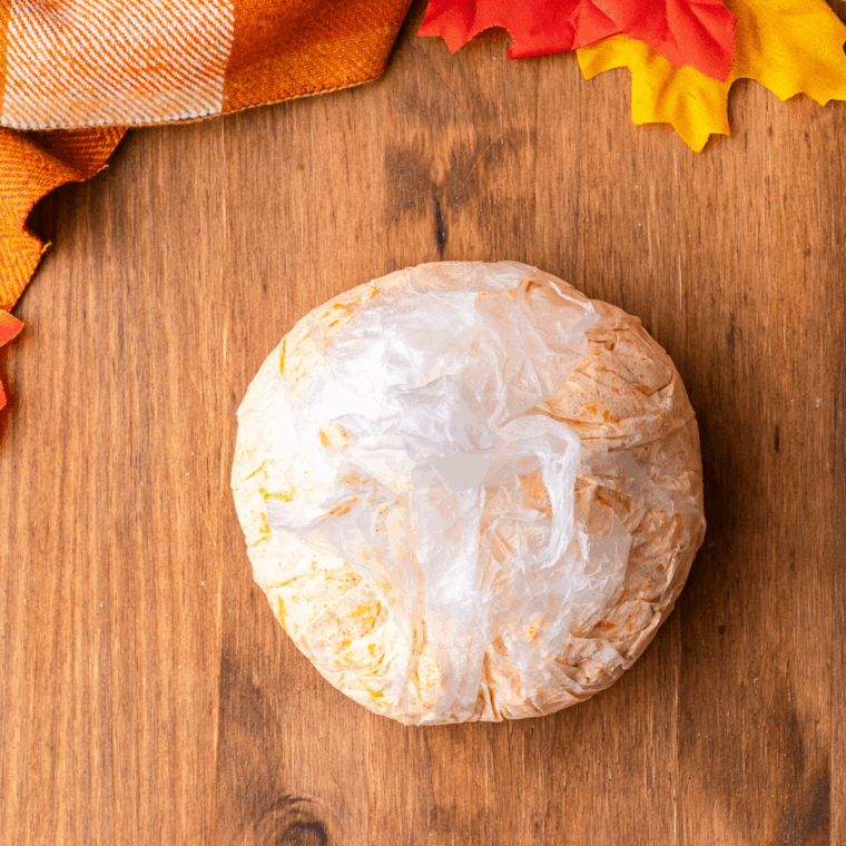 Shaping the cheese mixture into a round ball on plastic wrap and refrigerating to firm up.
