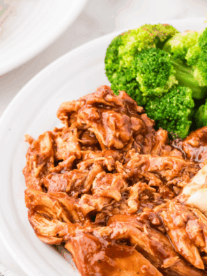 Slow cooker BBQ chicken shredded with barbecue sauce on a plate with a fork.