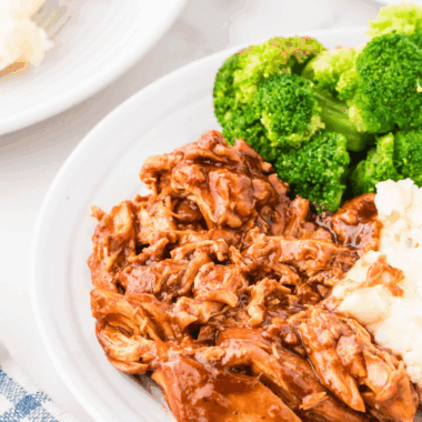 Slow cooker BBQ chicken shredded with barbecue sauce on a plate with a fork.