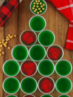 Festive sparkling Christmas tree Jello shots topped with glittery sugar on a holiday table.