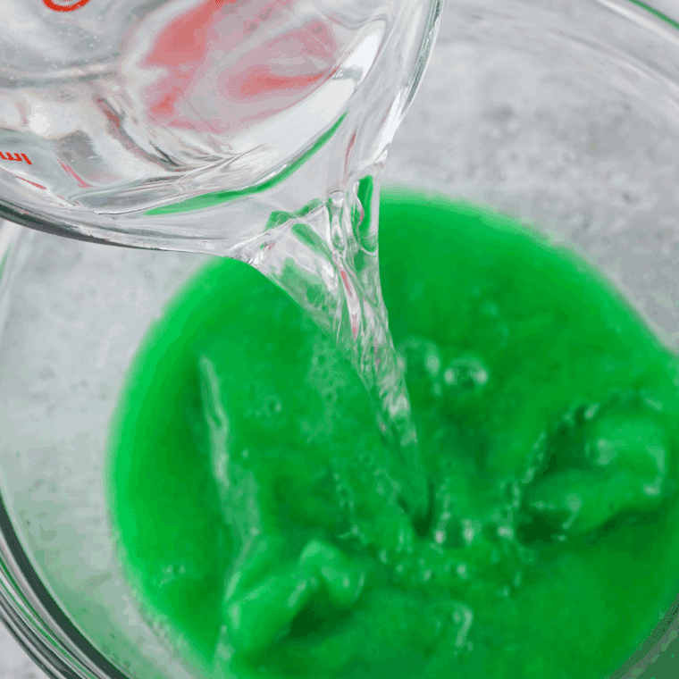 Pouring vodka into a bowl of dissolved lime Jello mixture for Jello shots.
