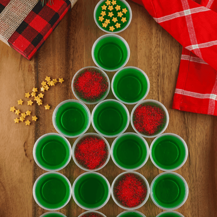 Festive sparkling Christmas tree Jello shots topped with glittery sugar on a holiday table.