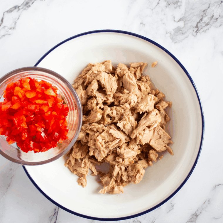 Flaking drained tuna in a large bowl with a fork for the sandwich.