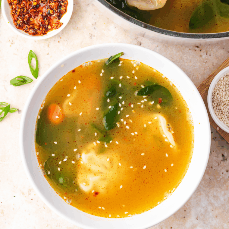 Bowl of Trader Joe’s Famous Wonton Soup with tender dumplings, carrots, green onions, and a lime wedge.