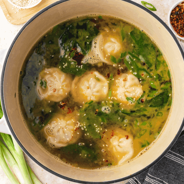 Bowl of Trader Joe’s Famous Wonton Soup with tender dumplings, carrots, green onions, and a lime wedge.