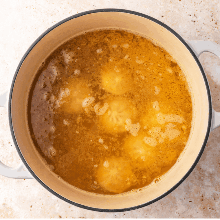 Frozen Trader Joe’s dumplings cooking in simmering broth until tender and heated through.