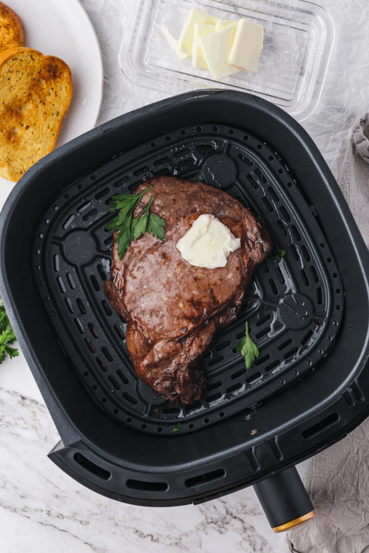 Air fryer smoking while cooking food inside the basket on a kitchen counter.