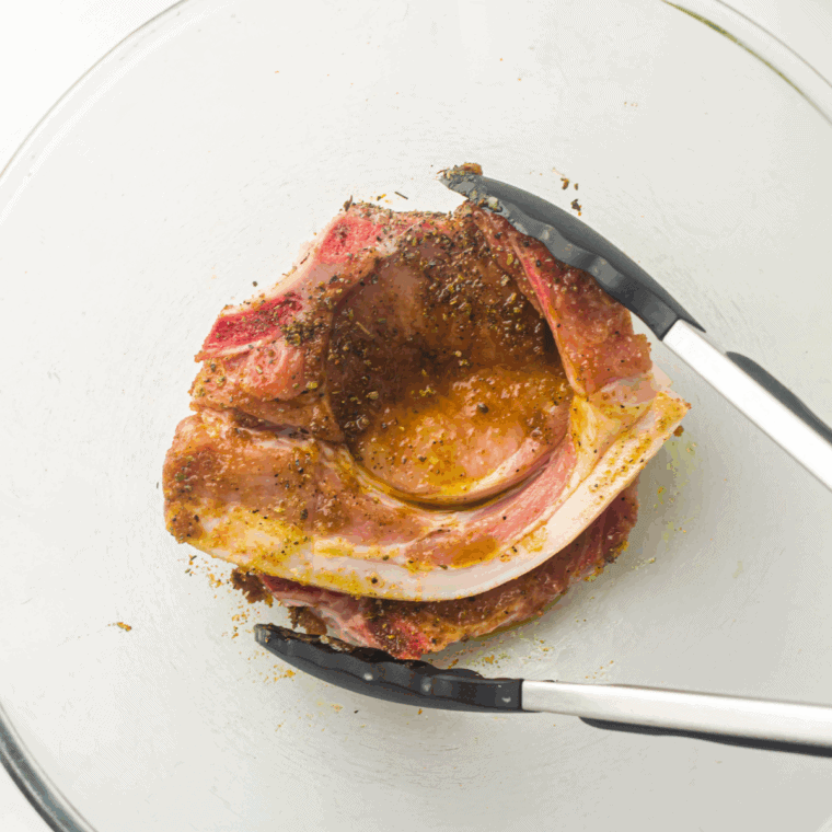 Rubbing Kinder&rsquo;s The Blend Mix on the pork chops.