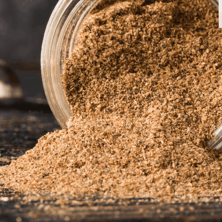 A small white bowl filled with the coarse, dark brown Copycat Kinder&rsquo;s The Blend seasoning mix, showing visible herbs, cracked pepper, and spices.