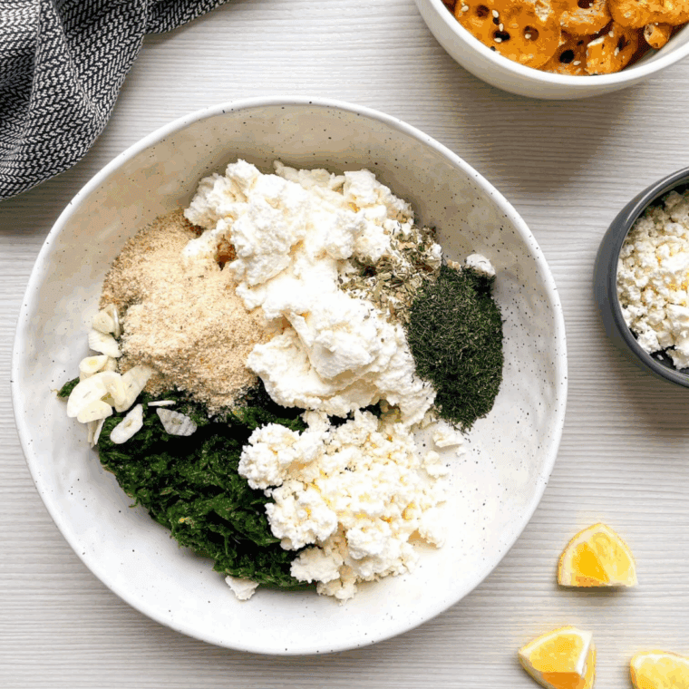 Mixing spinach, ricotta, feta, garlic, herbs, and seasonings in a bowl.