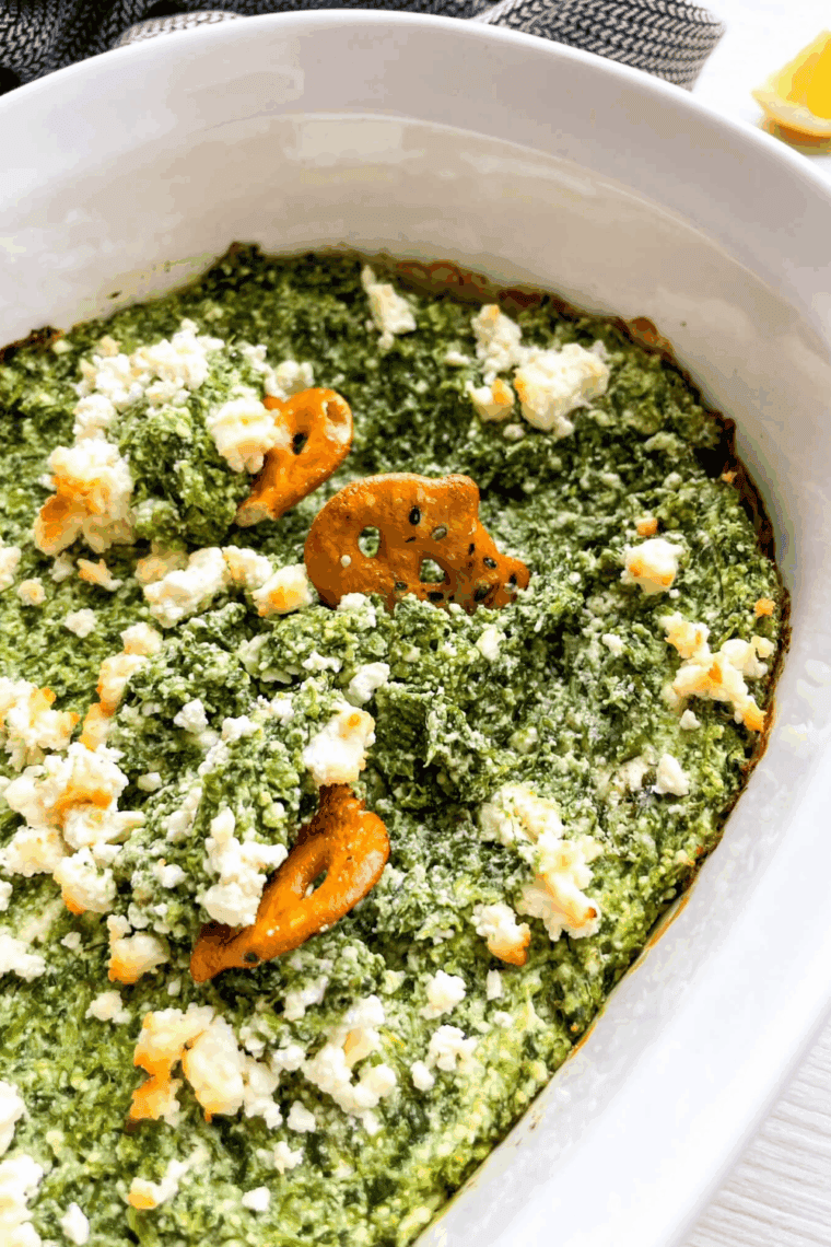 Creamy Spanakopita Dip baked in a casserole dish, topped with crumbled feta and herbs, ready to serve.