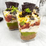 Individual 7 Layer Dip Cups with beans, cheese, guacamole, and fresh toppings.