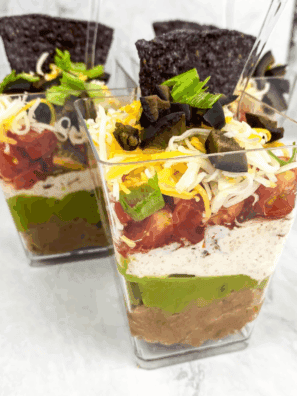Individual 7 Layer Dip Cups with beans, cheese, guacamole, and fresh toppings.