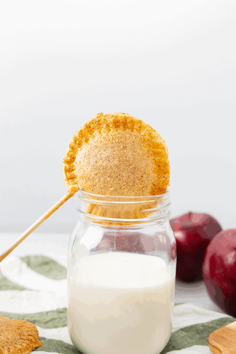 Powdered sugar glaze being drizzled over warm, golden apple pop-tarts.