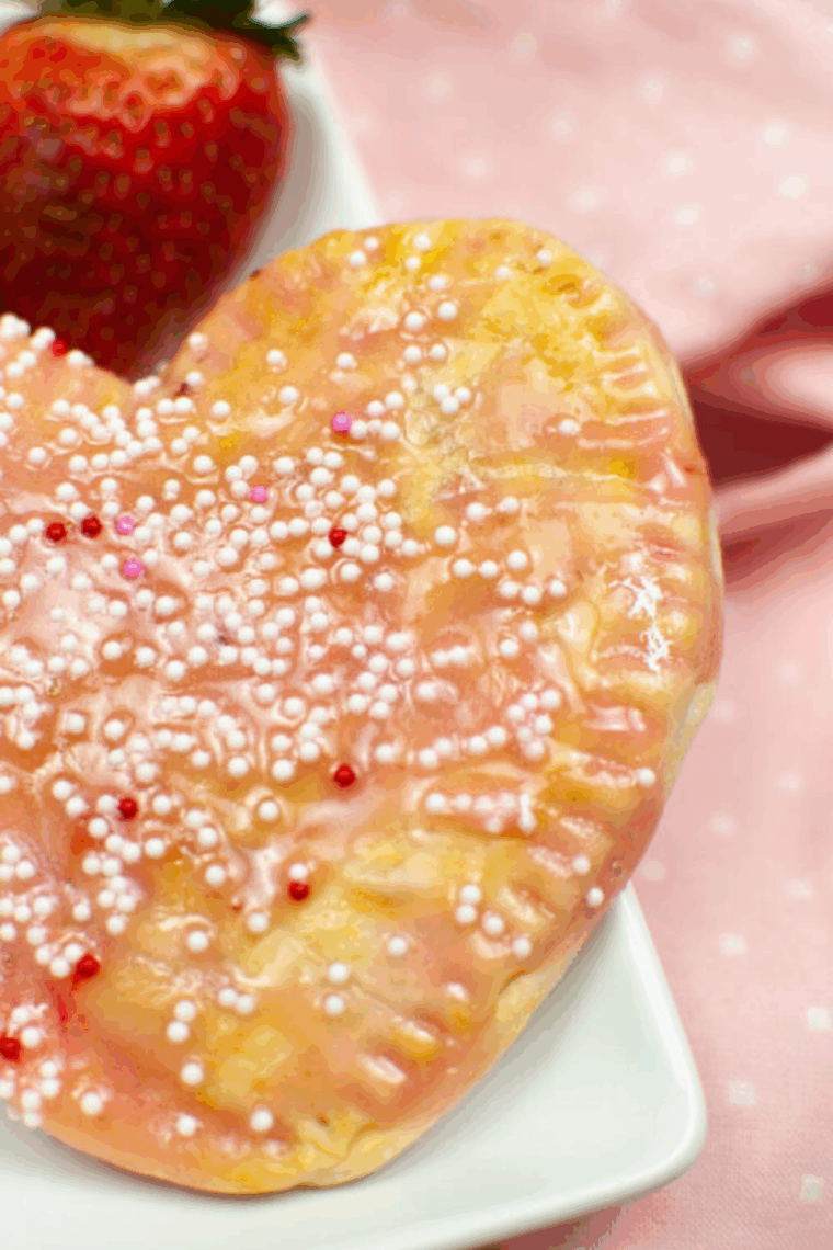 Golden air fryer cranberry pop-tarts topped with glaze and festive sprinkles, filled with tart cranberry jam.