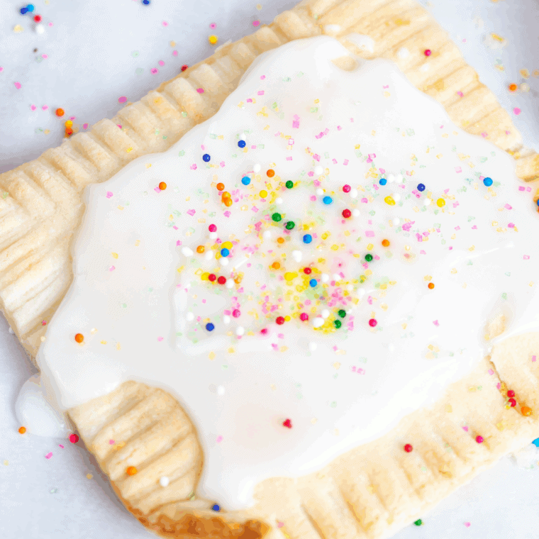 Golden air fryer raspberry pop-tarts drizzled with glaze and topped with colorful sprinkles on a plate.