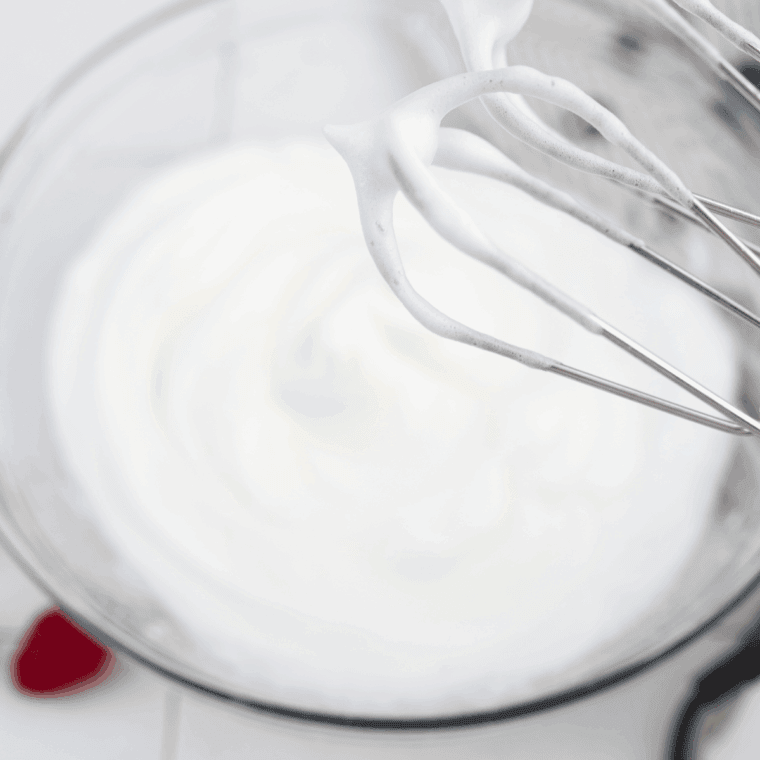 Egg whites whipped to stiff peaks using a hand mixer.