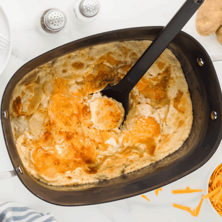 Golden brown and bubbly baked dish of Ruth's Chris style Potatoes au Gratin, showing layers of sliced potatoes covered in creamy cheese sauce.