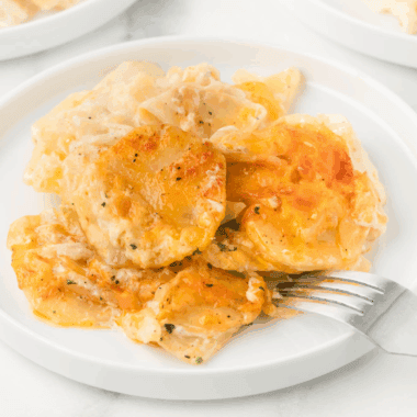 Golden brown and bubbly baked dish of Ruth's Chris style Potatoes au Gratin, showing layers of sliced potatoes covered in creamy cheese sauce.