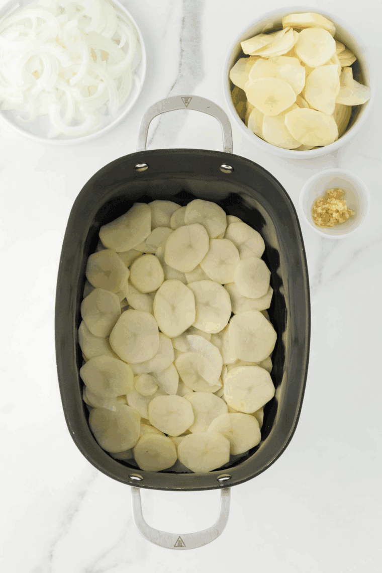 Greased crockpot ready for potatoes and cheese layers