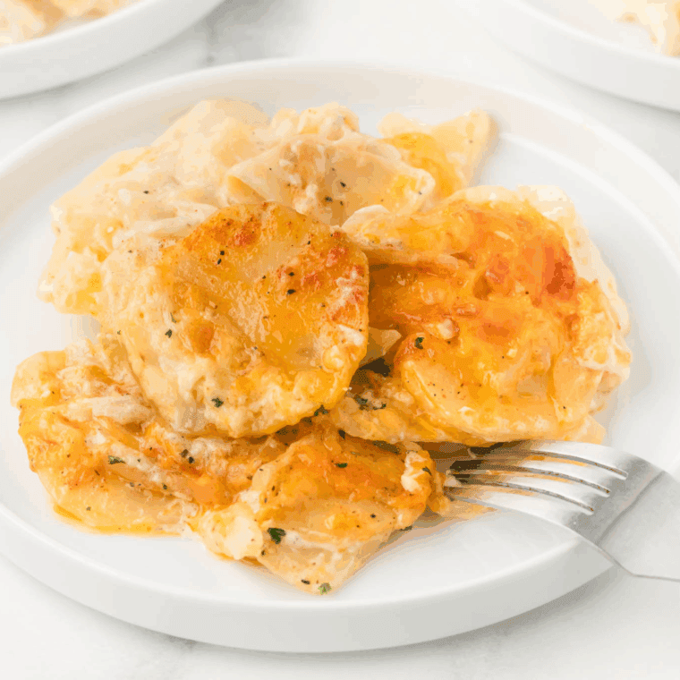 Golden brown and bubbly baked dish of Ruth's Chris style Potatoes au Gratin, showing layers of sliced potatoes covered in creamy cheese sauce.