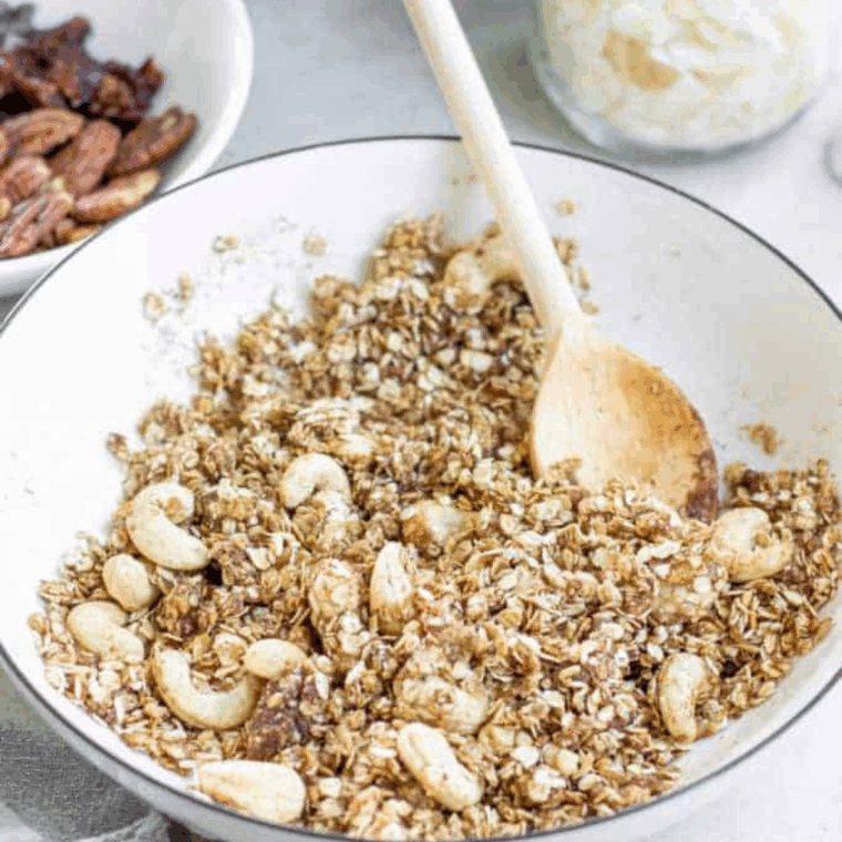Melting coconut oil, agave syrup, maple syrup, and vanilla in a saucepan and combining with dry ingredients until fully coated.