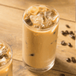 Glass of First Watch-style iced coffee with ice cubes and a splash of milk.