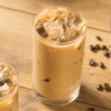 Glass of First Watch-style iced coffee with ice cubes and a splash of milk.