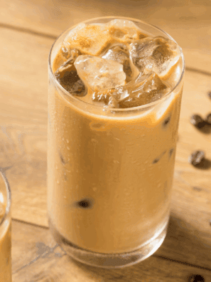 Glass of First Watch-style iced coffee with ice cubes and a splash of milk.