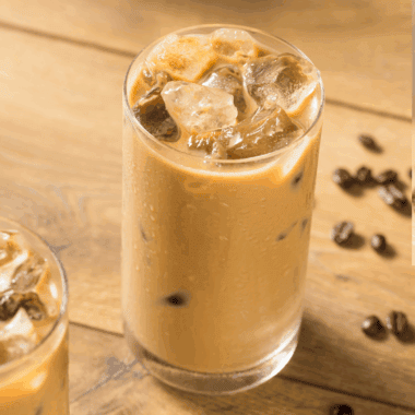 Glass of First Watch-style iced coffee with ice cubes and a splash of milk.