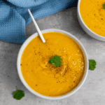 Bowl of creamy Ina Garten-inspired butternut squash soup garnished with herbs.