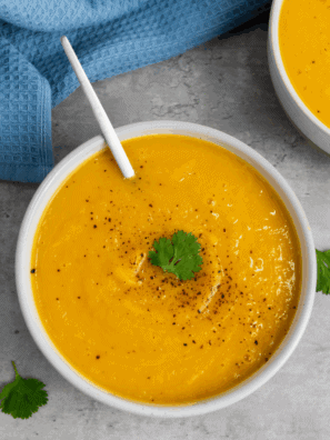 Bowl of creamy Ina Garten-inspired butternut squash soup garnished with herbs.