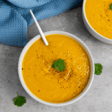 Bowl of creamy Ina Garten-inspired butternut squash soup garnished with herbs.
