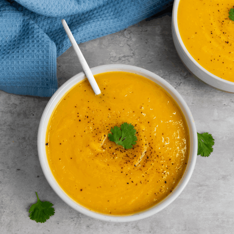 Bowl of creamy Ina Garten-inspired butternut squash soup garnished with herbs.