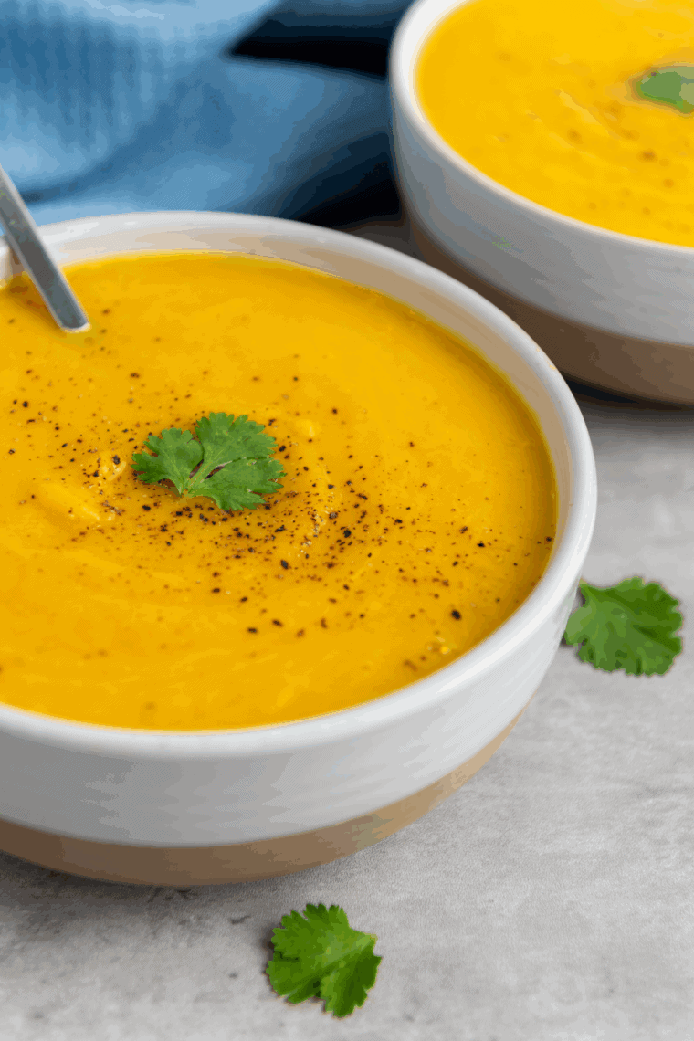 Bowl of creamy butternut squash soup garnished with herbs, ready to serve