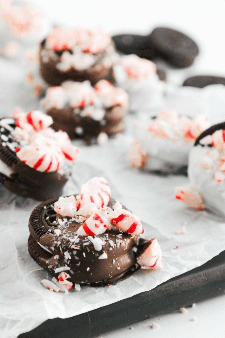 Peppermint Chocolate Covered Oreos with crushed candy canes on a festive plate