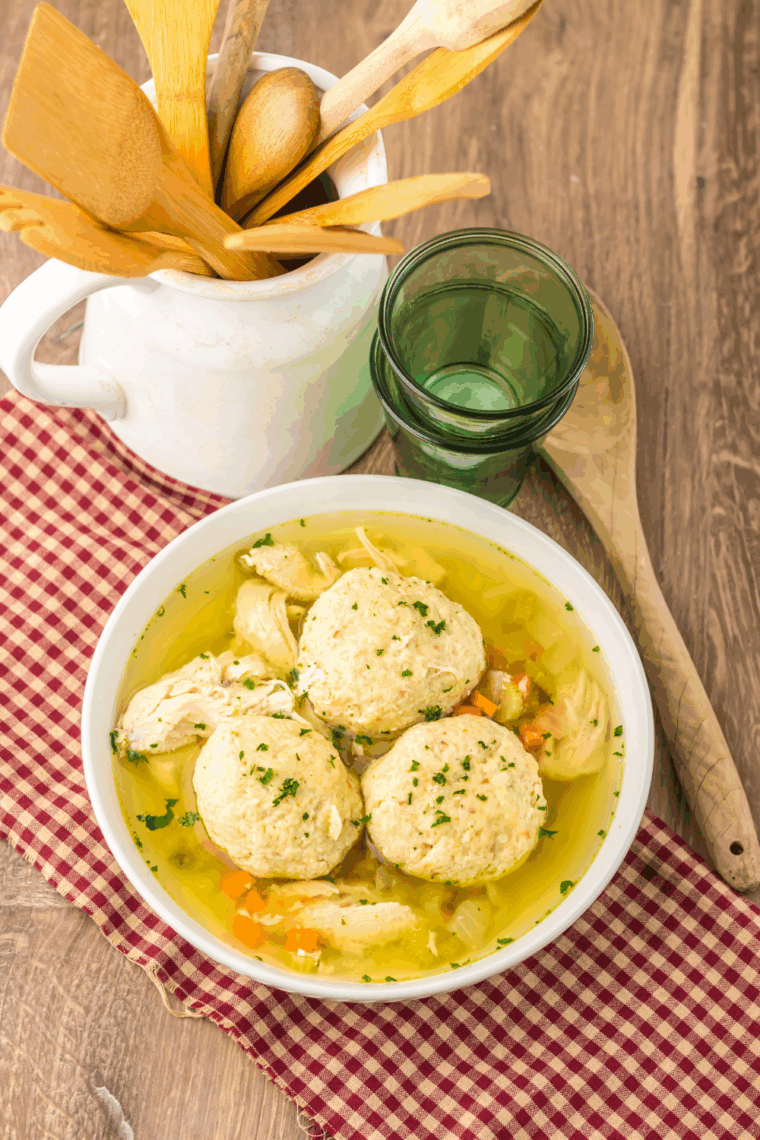 Bowl of traditional Slow Cooker Matzo Ball Soup with fluffy matzo balls, shredded chicken, and fresh dill.