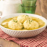 Bowl of traditional Slow Cooker Matzo Ball Soup with fluffy matzo balls, shredded chicken, and fresh dill.