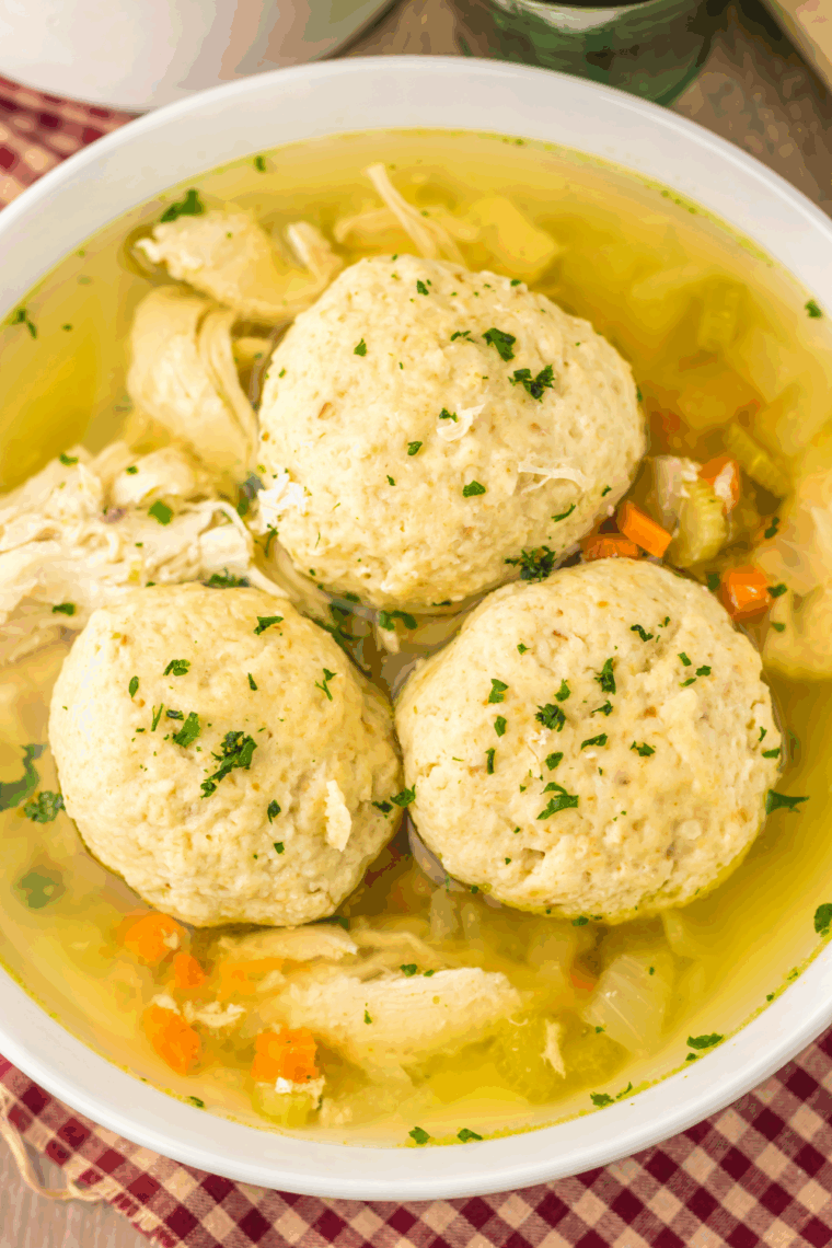 Close-up of a tender matzo ball resting in a clear, golden chicken broth.